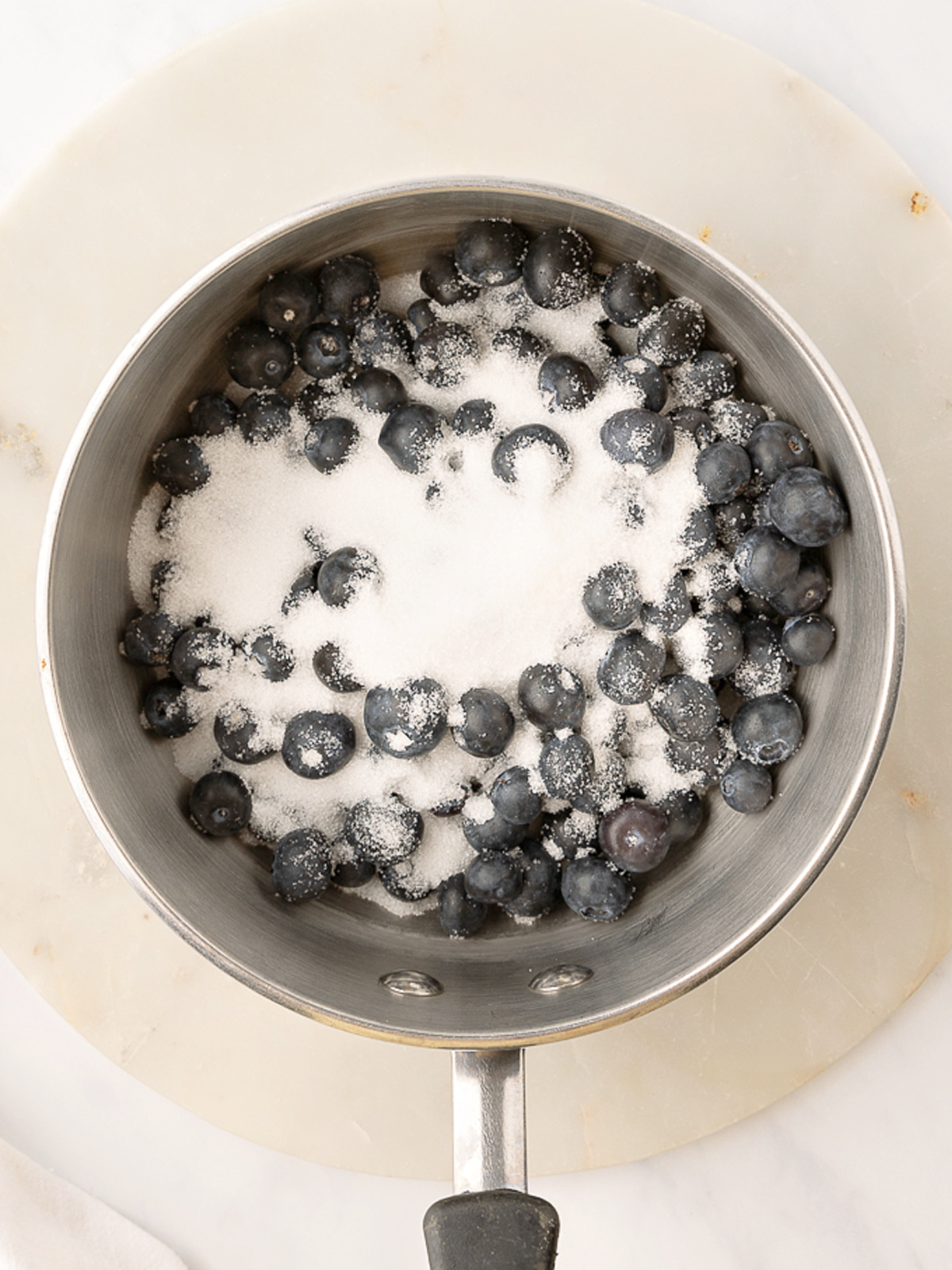 Blueberries and sugar in a small pot.