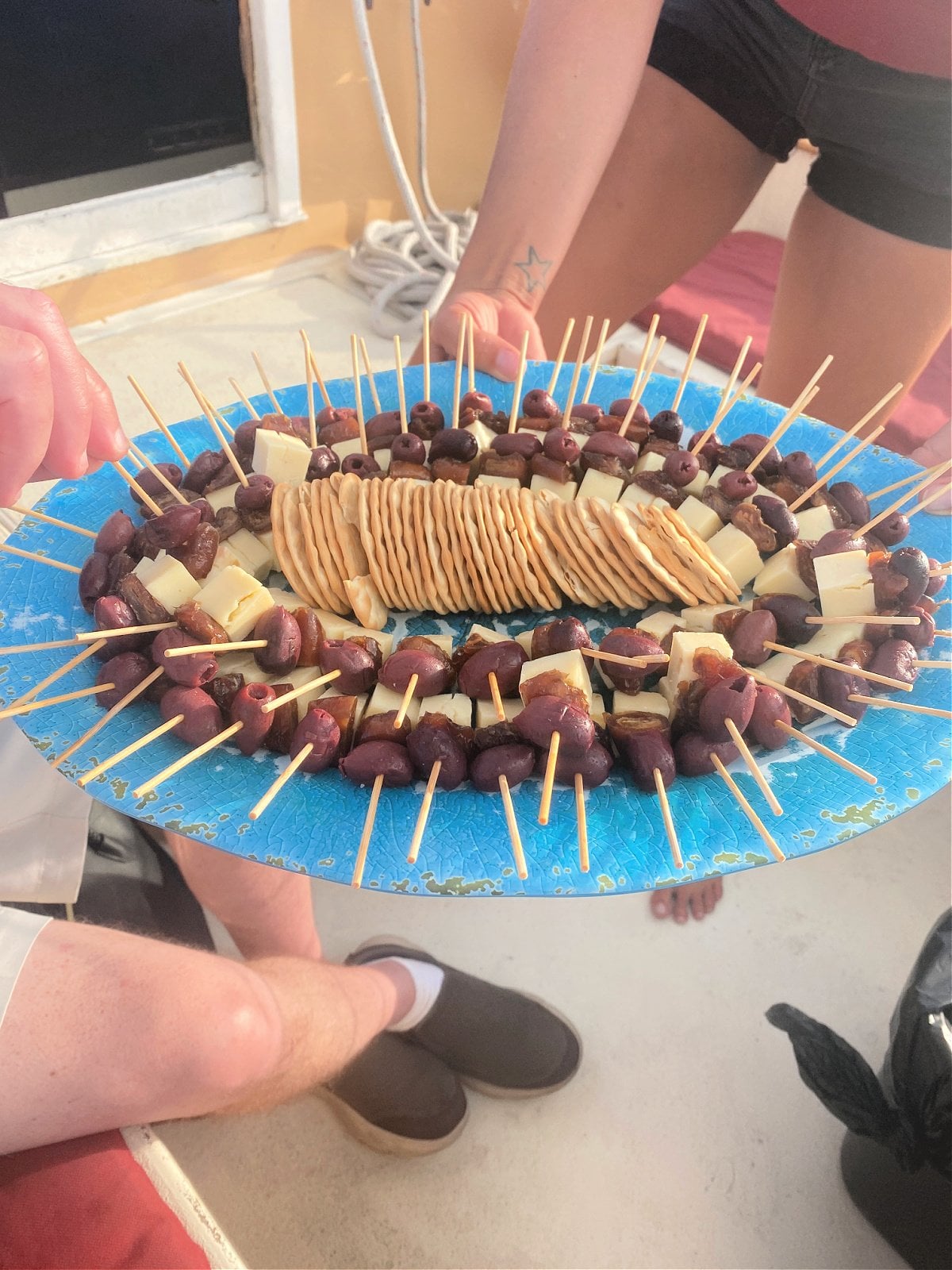 A platter of crackers and hors d'oeuvres on sticks.