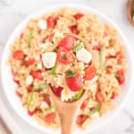 A spoonful of caprese pasta salad made with tomatoes, mozzarella, and basil.