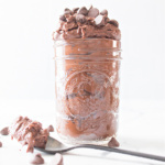A jar filled with edible brownie batter and a spoon with a scoop of batter.
