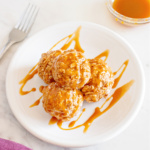 Plate of ice cream balls topped with caramel sauce.