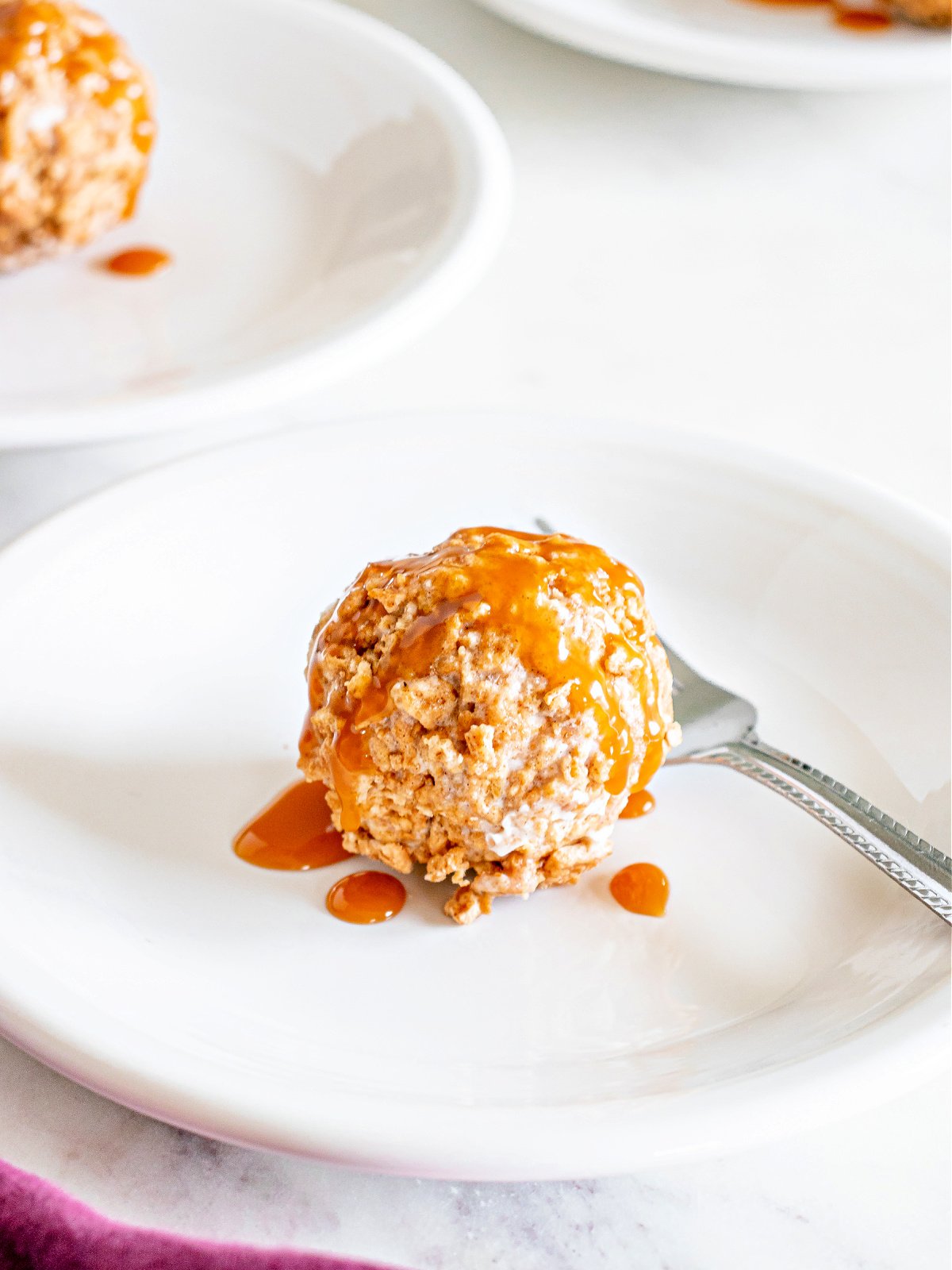 An ice cream ball topped with caramel sauce on a plate.