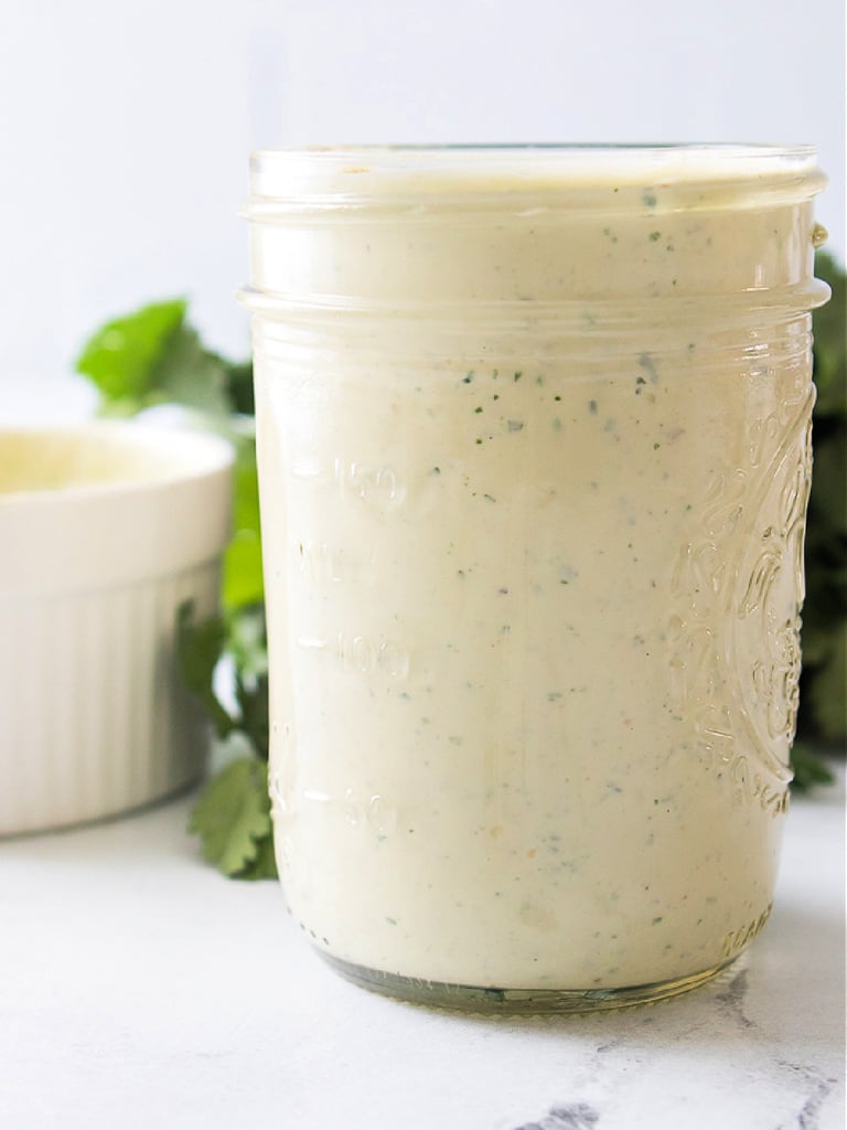 Glass jar filled with homemade jalapeño ranch dressing on a countertop.