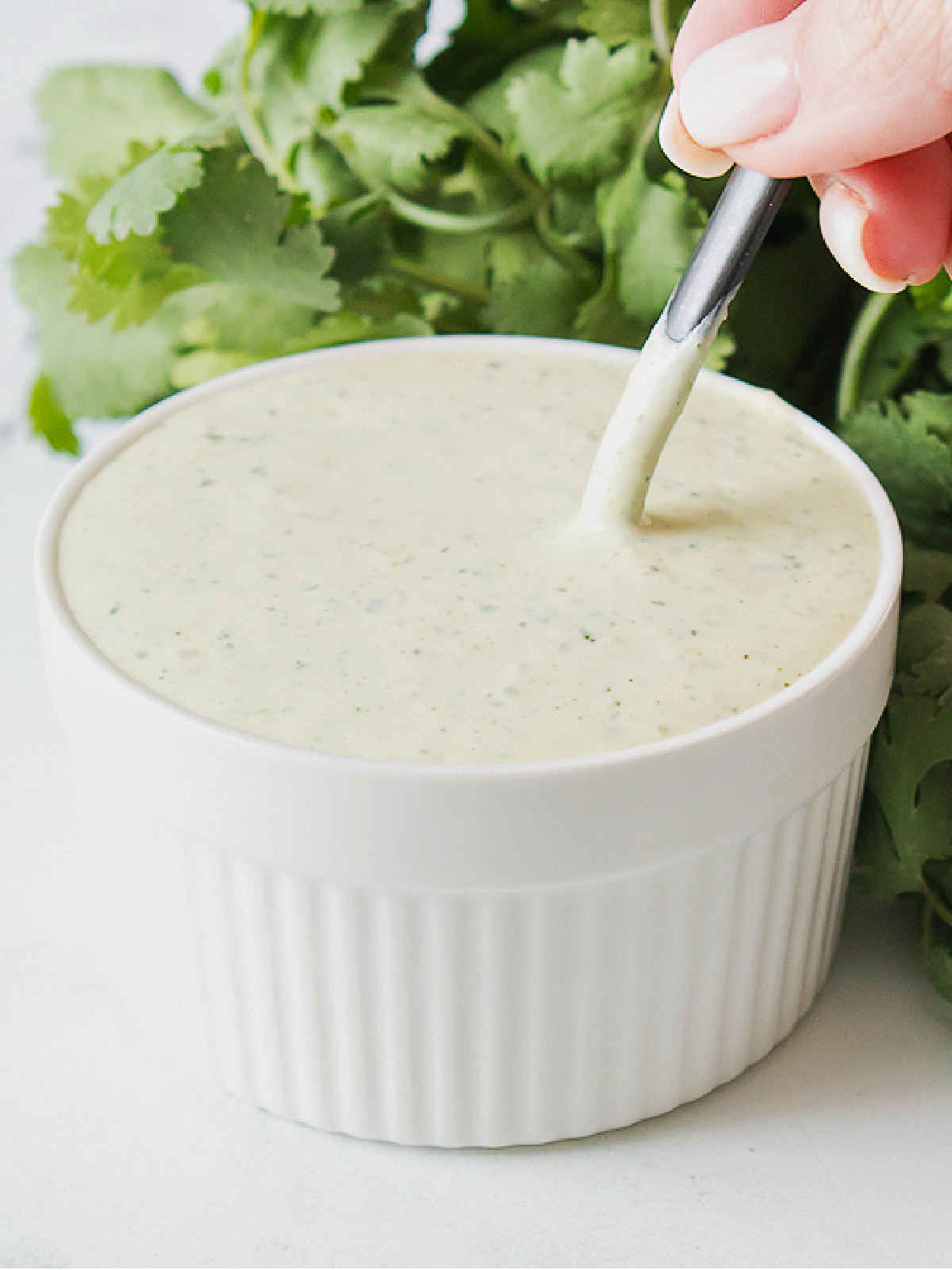 Spoon stirring jalapeño ranch dressing in a small bowl.
