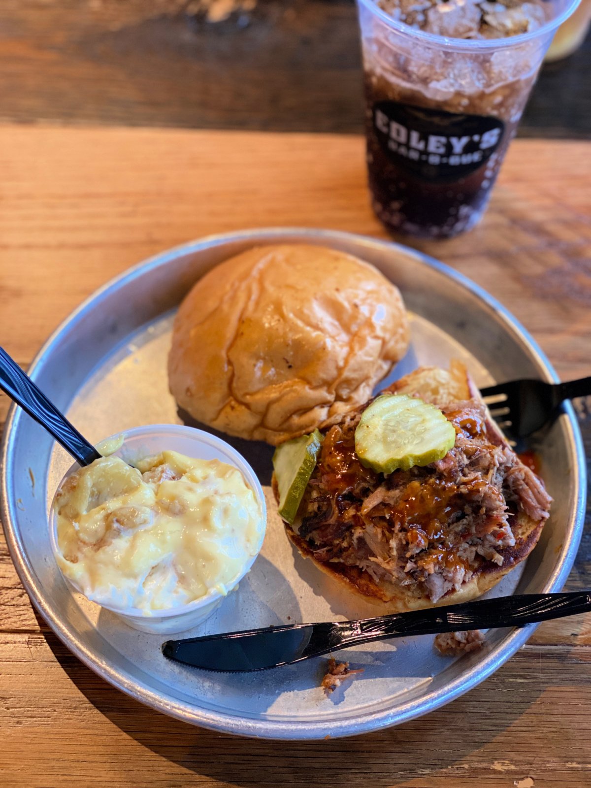 BBQ sandwich on a plate with a cup of banana pudding.