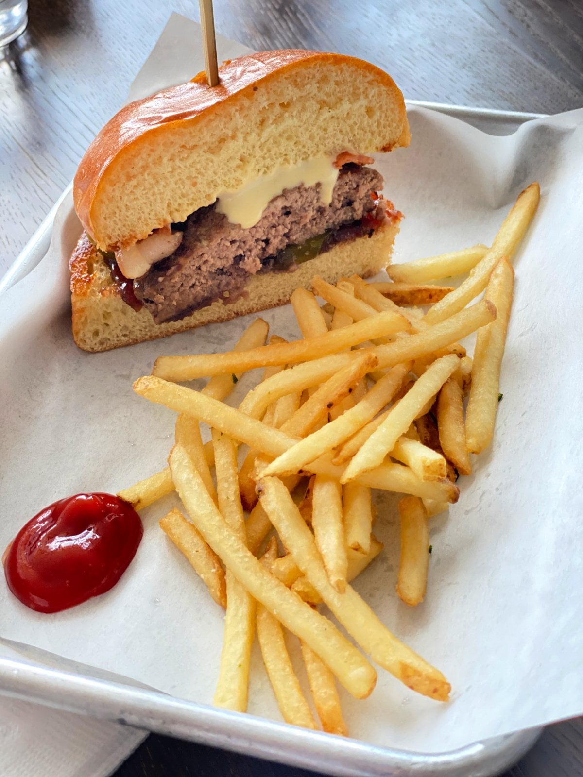 Hamburger and French fries on a silver tray.