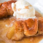Two apple dumplings in a bowl with a scoop of ice cream.