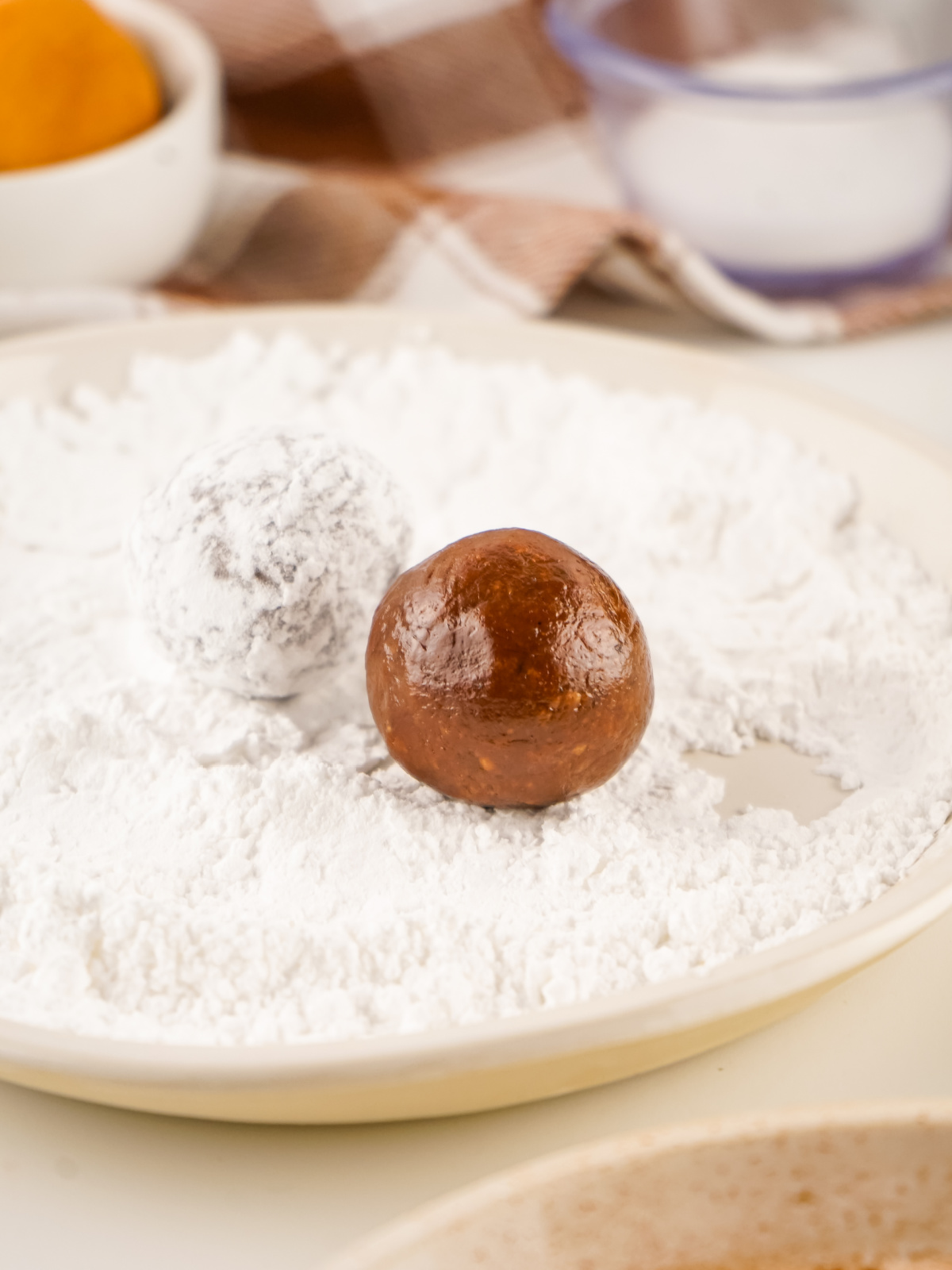 Rum balls being coated in powdered sugar.