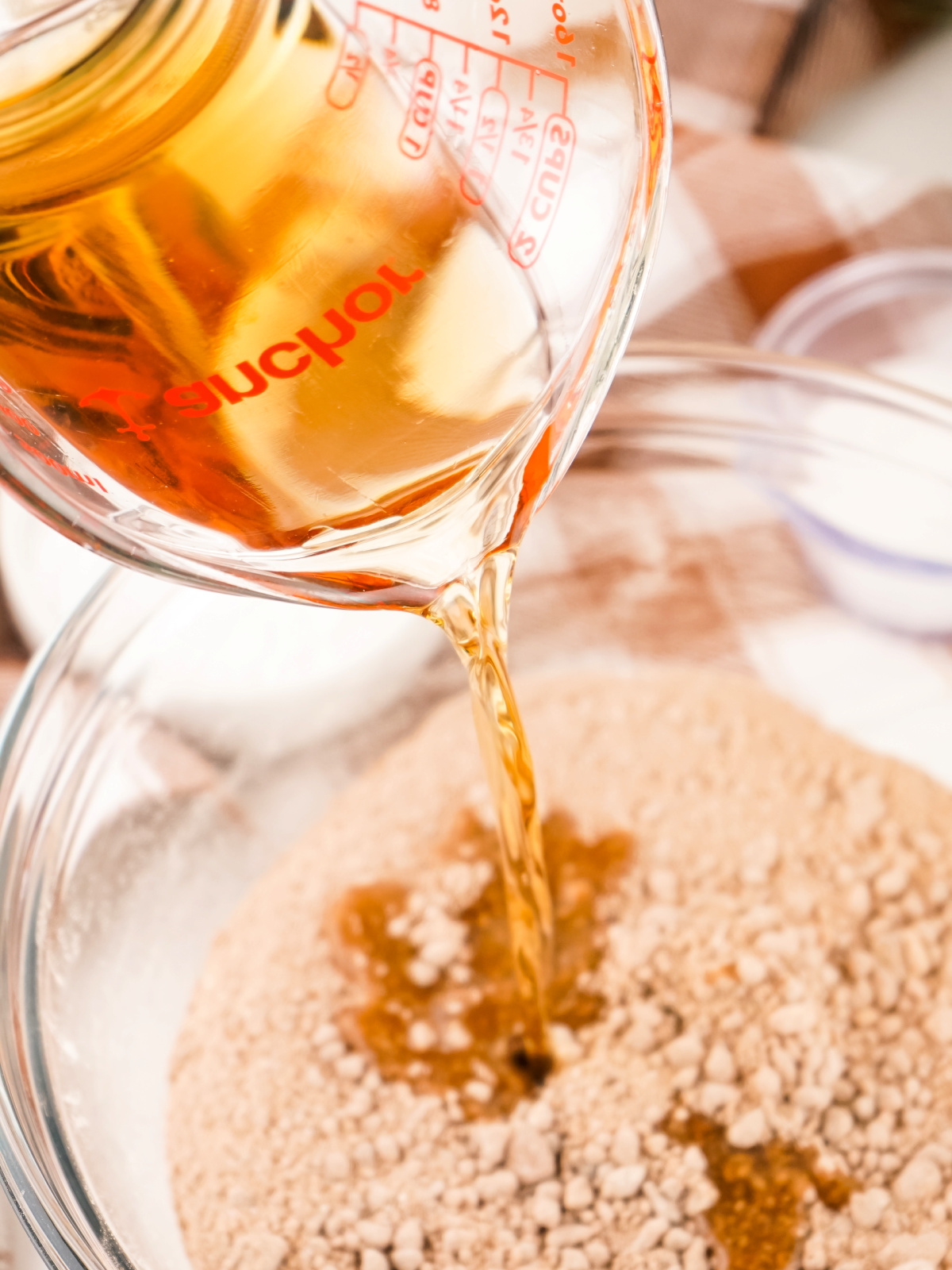 Rum being poured into a bowl with ingredients to make rum balls.