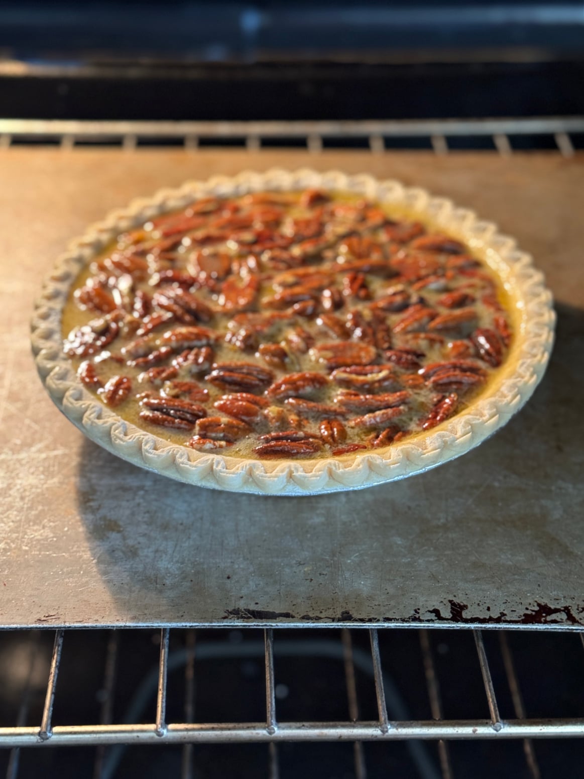 Unbaked pecan pie being placed in an oven.