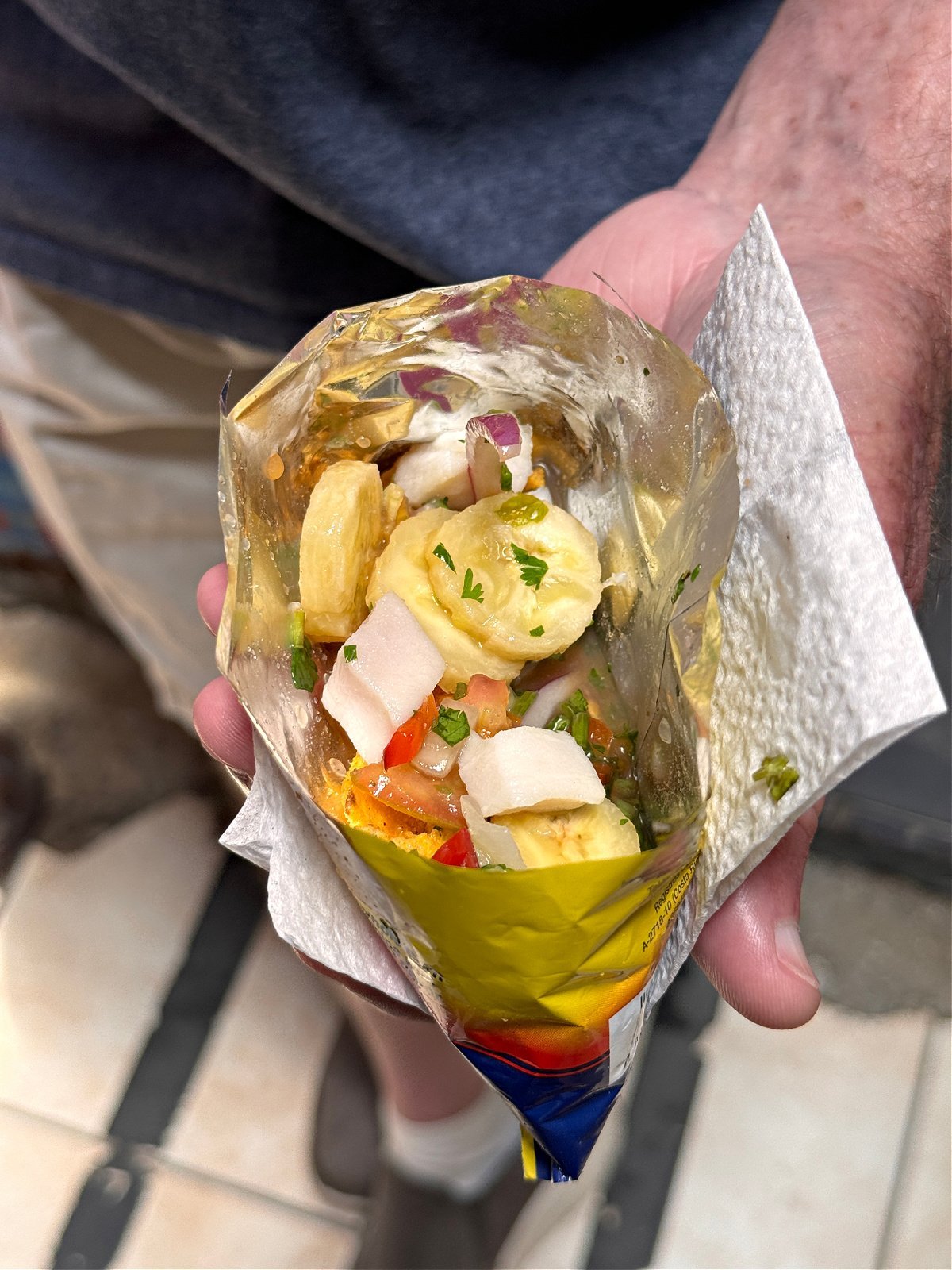 Man holding a bag of chips topped with ceviche.