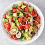 Salad made with avocado, cucumber, red onion, and seasoning.