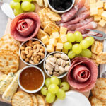 Close up look at a charcuterie board filled with fruits, nuts, meats, and cheese.
