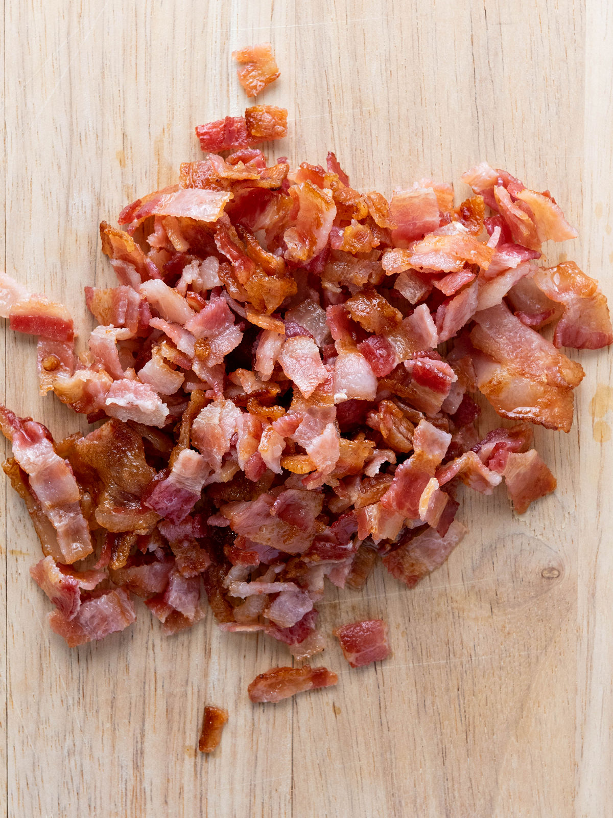 Chopped bacon on a wooden cutting board.