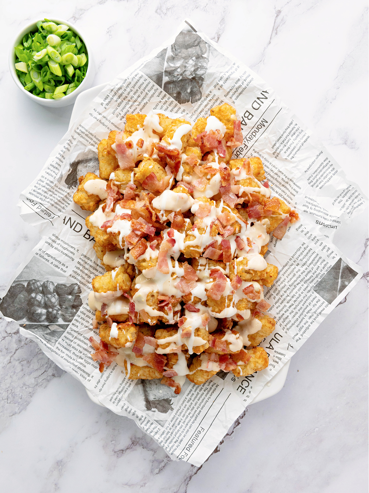 Baked tater tots topped with bacon, Ranch dressing, and queso.