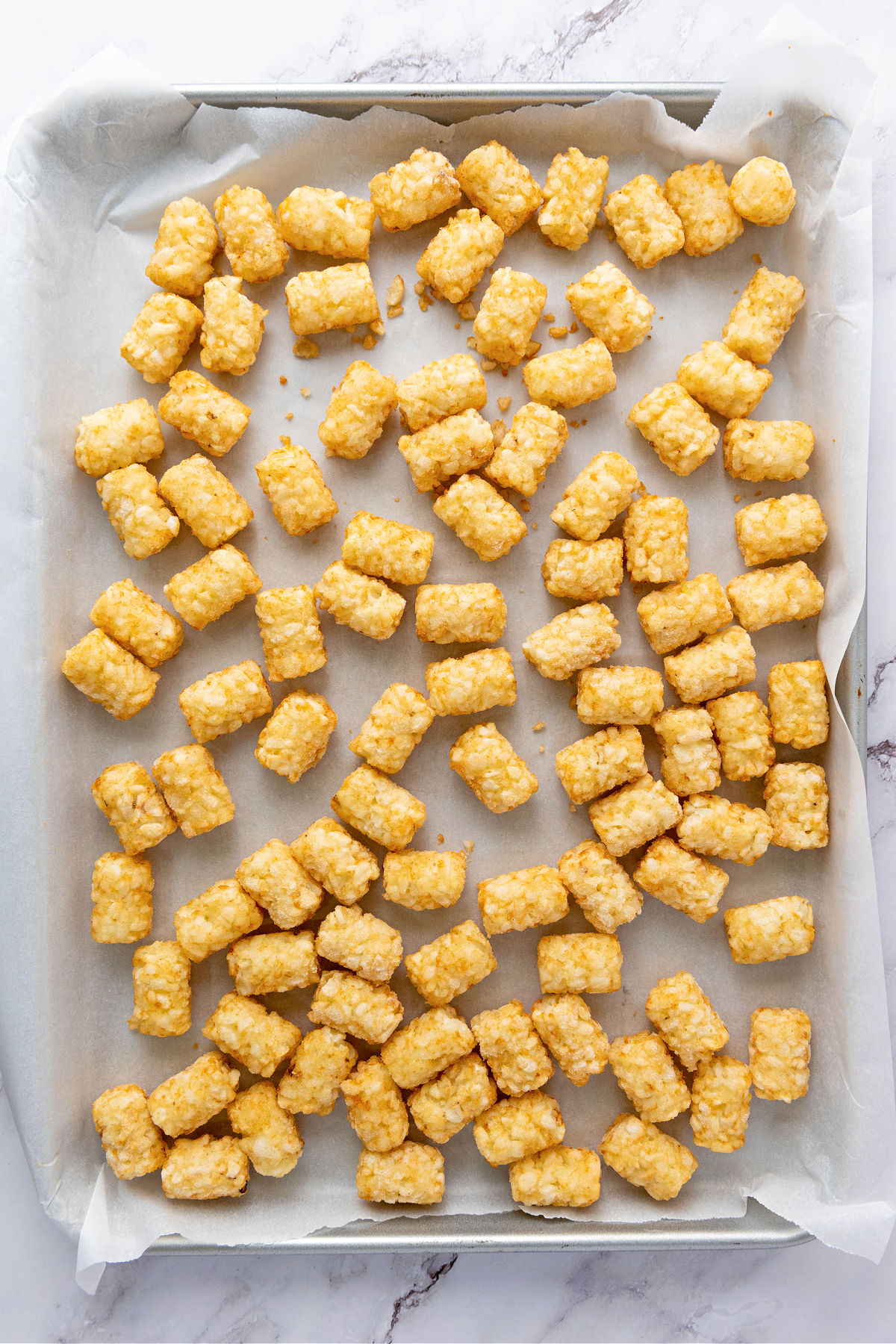 Frozen tater tots on a parchment lined baking sheet.