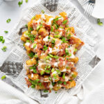 Loaded tater tots on a piece of parchment paper.