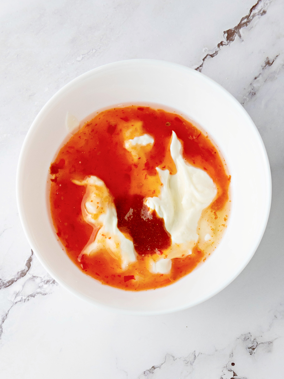 Mayonnaise, sriracha sauce, and sweet chili in a small bowl.