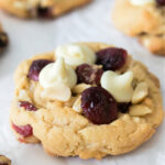 White chocolate cranberry cookies with macadamia nuts on a sheet of parchment paper.