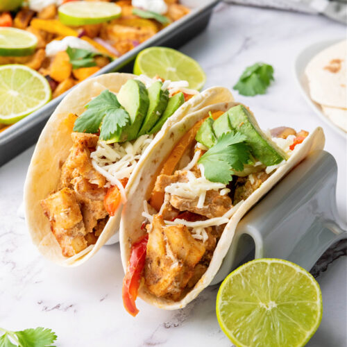 Two chicken fajitas in a taco stand.