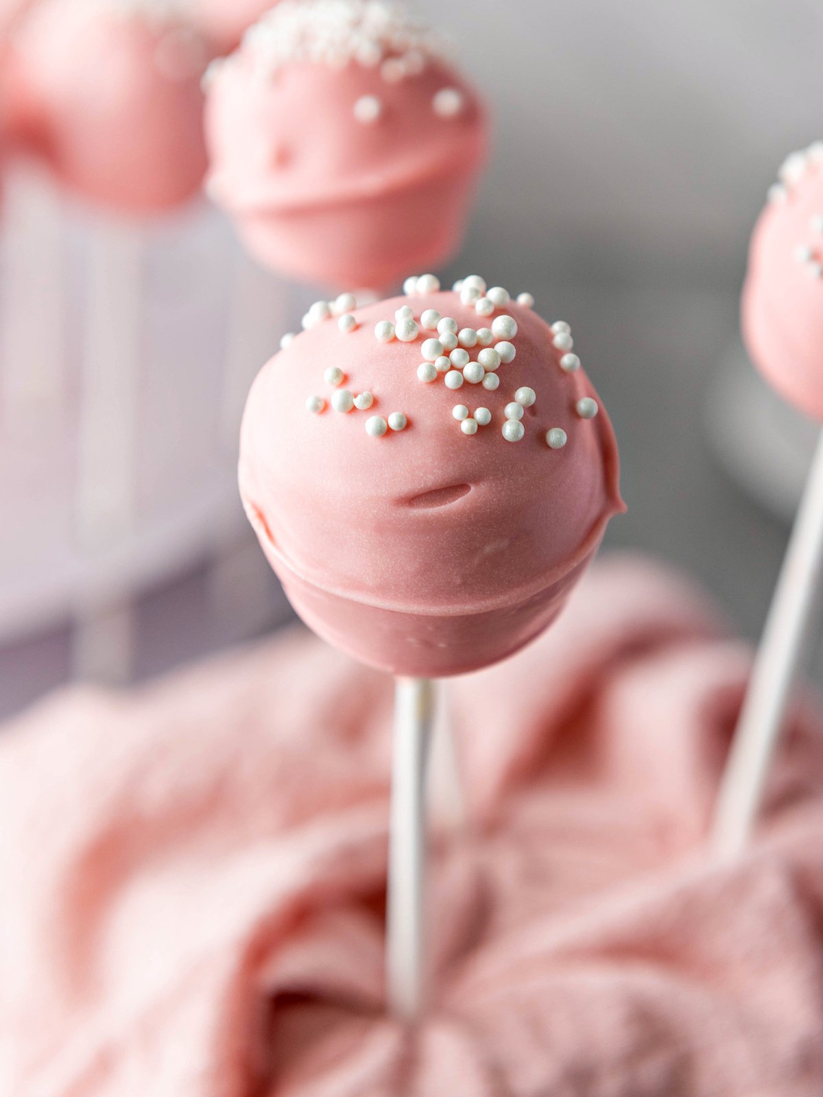 Pink cake pop topped with white nonpareils.