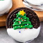 Festive Oreo cookie decorated with a green Christmas tree and topped with a yellow star and sprinkles.