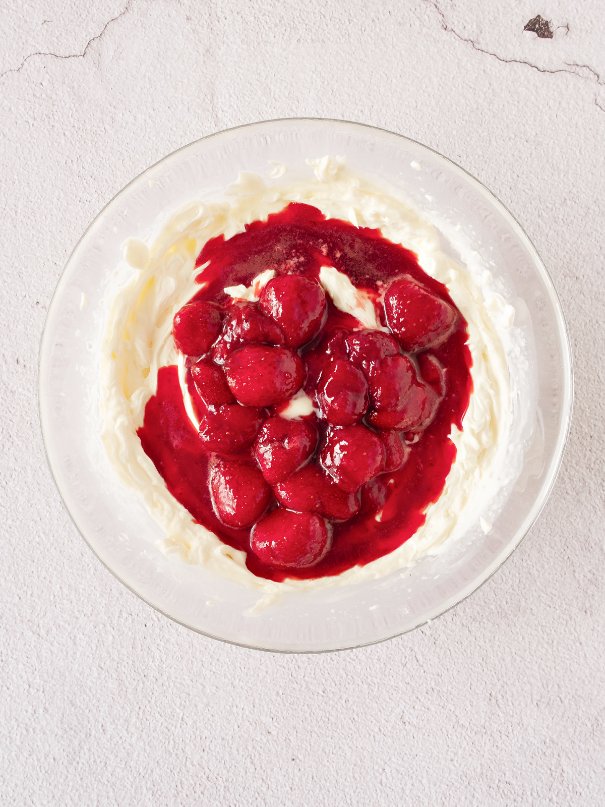 Close-up of whipped mascarpone cream being folded with strawberry puree.