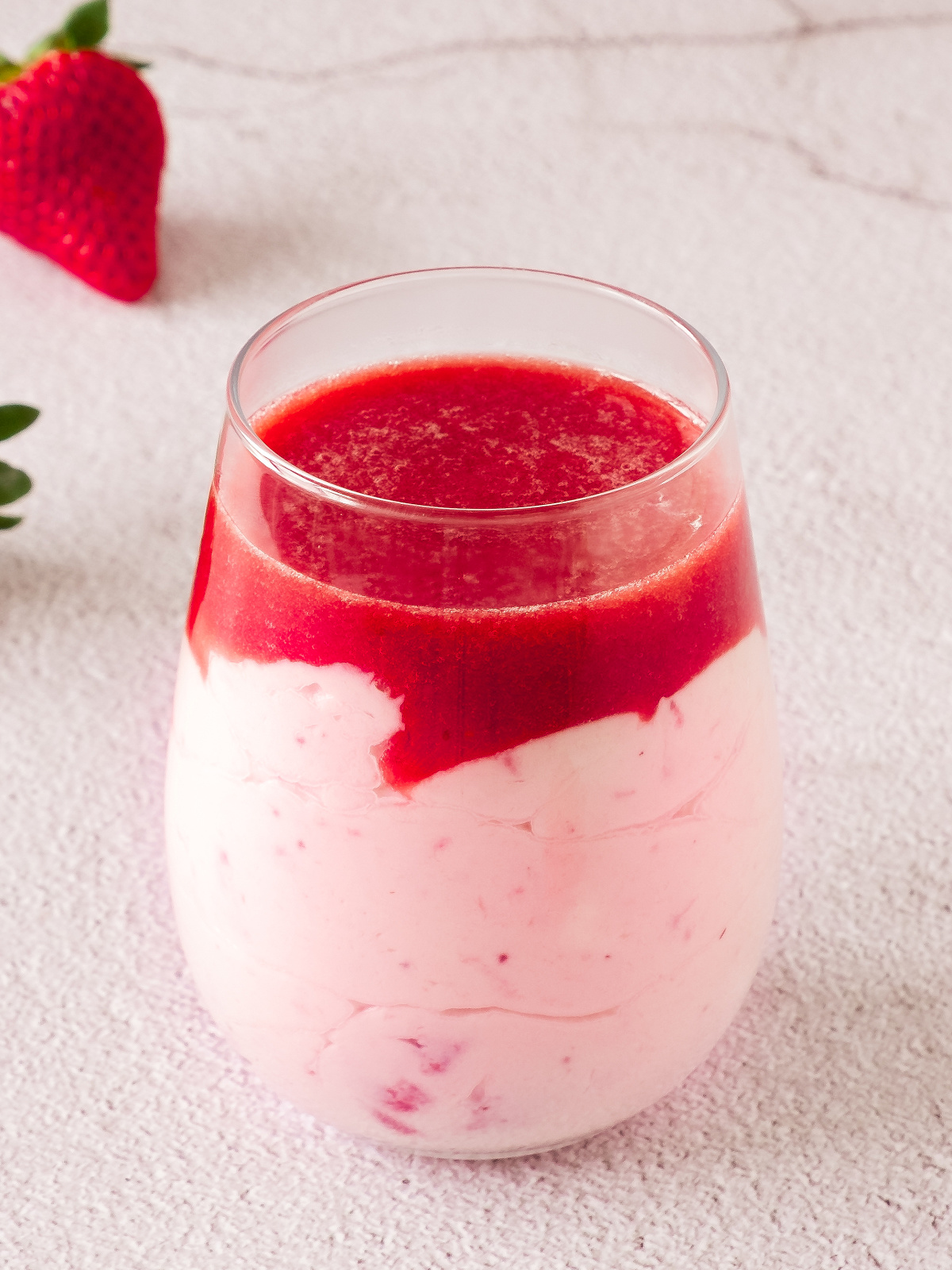 Glass filled with strawberry mousse and topped with pureed strawberries cooked with gelatin.