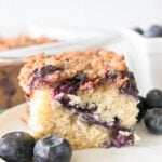 Slice of blueberry buckle on a small white plate.