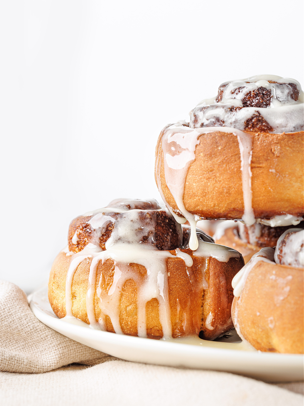 Stack of freshly baked cinnamon rolls with cream cheese icing.
