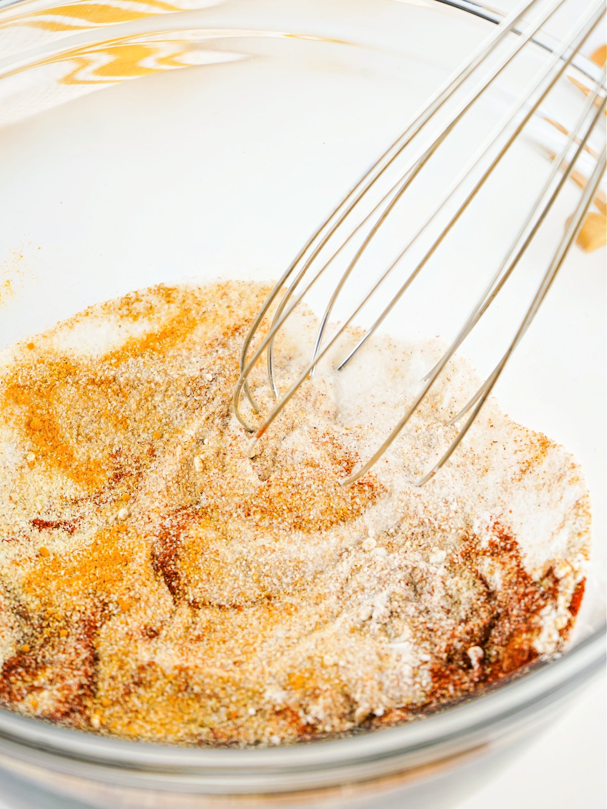Seasonings being whisked together in a glass mixing bowl.