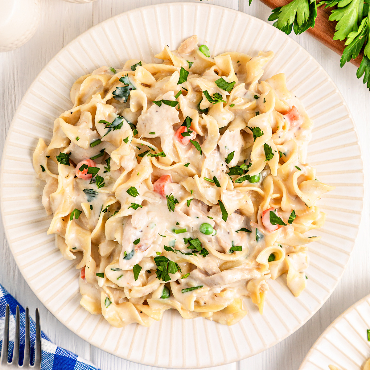 Plate of tuna noodles with carrots and peas.