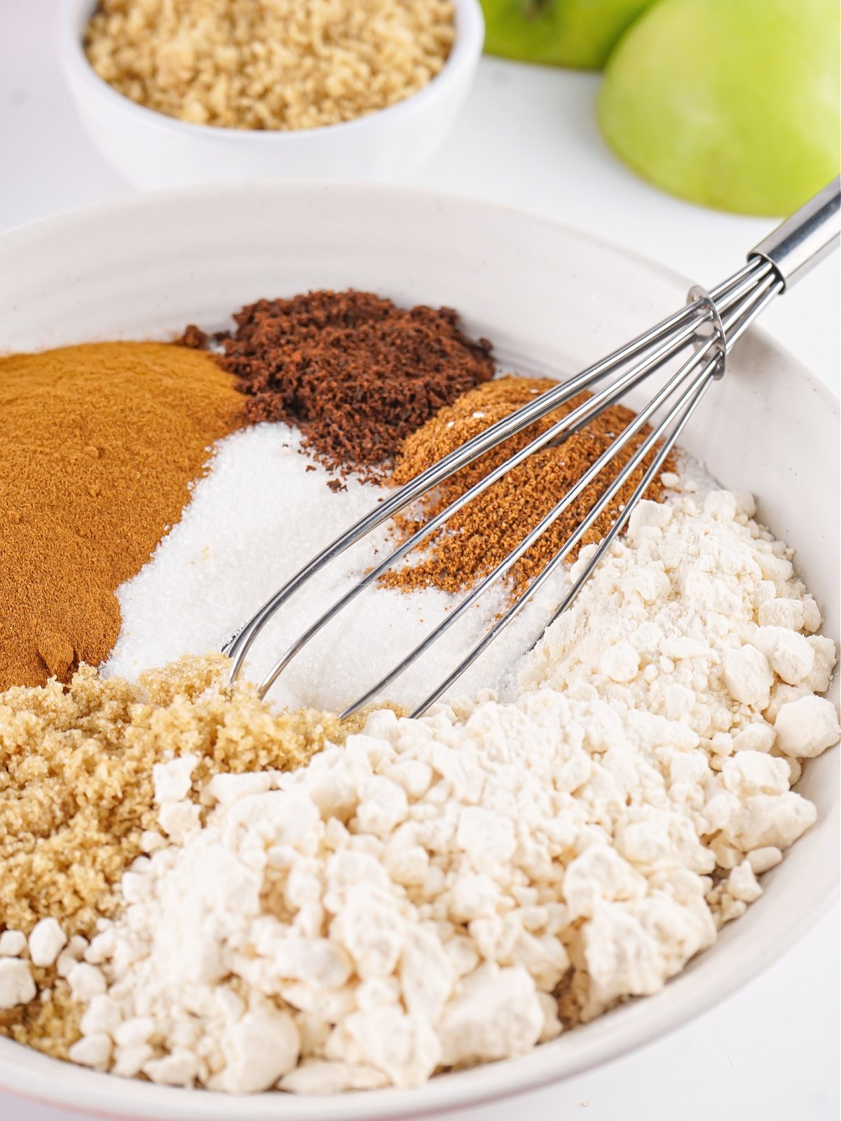 Ingredients to make apple cider mix in a bowl with a whisk.