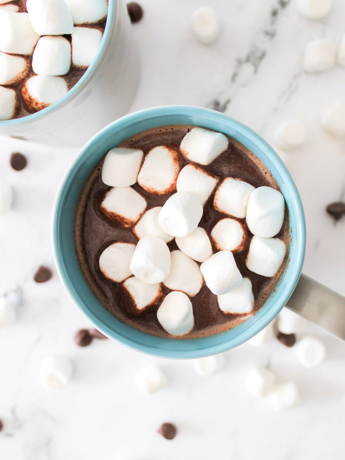 Close-up of creamy hot chocolate in a mug, topped with a generous layer of tiny marshmallows.