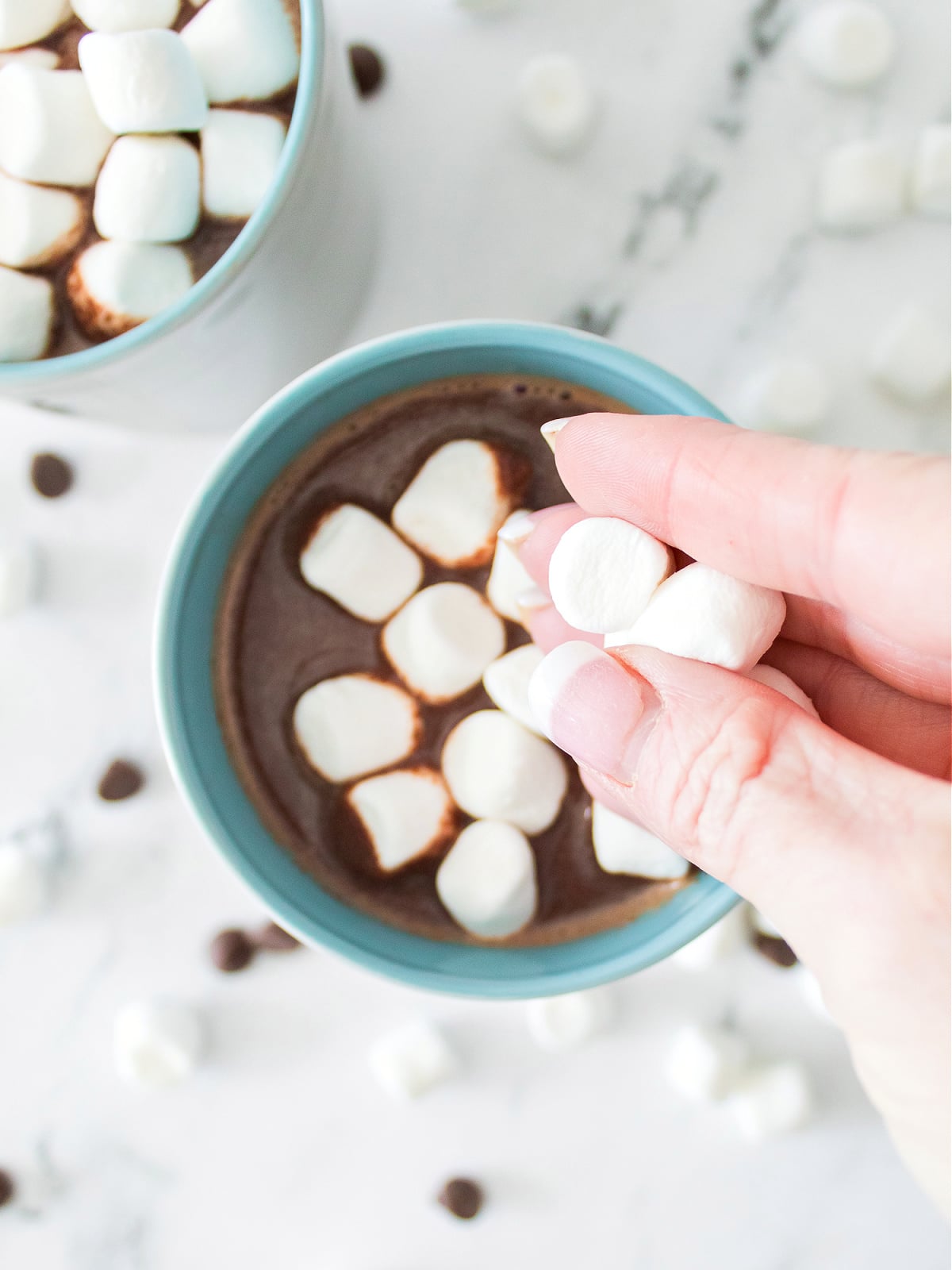 Mini marshmallows falling into a steaming cup of homemade hot chocolate.