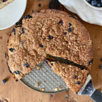 A pie server taking a piece of blueberry coffee cake.
