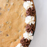 Chocolate and white frosting around the border of a chocolate chip cookie.