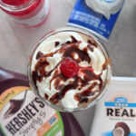 Cherry on top of whipped cream in a glass.