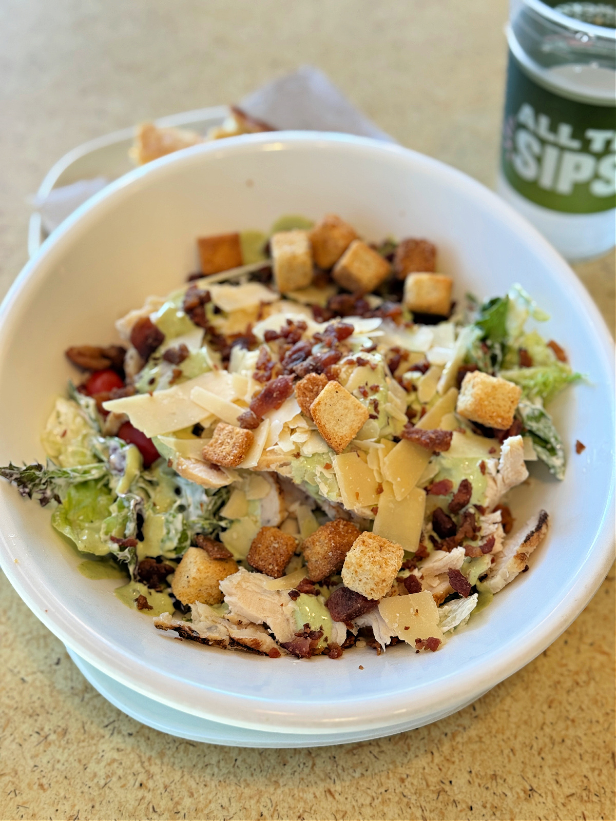 Bowl of mixed greens and romaine tossed in ranch, topped with sliced chicken, grape tomatoes, applewood smoked bacon, shaved parmesan, croutons, and drizzled with Green Goddess dressing.