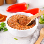 Wooden spoon scooping homemade BBQ rub from a bowl.