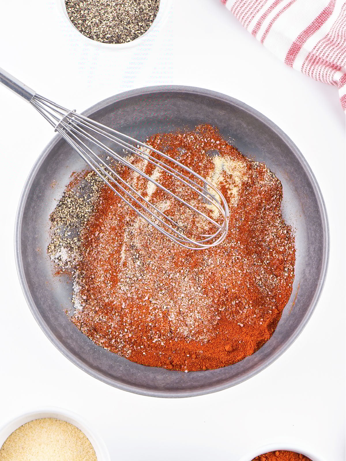 Whisk resting in a bowl of partially mixed barbecue spices for classic 5-ingredient BBQ rub.