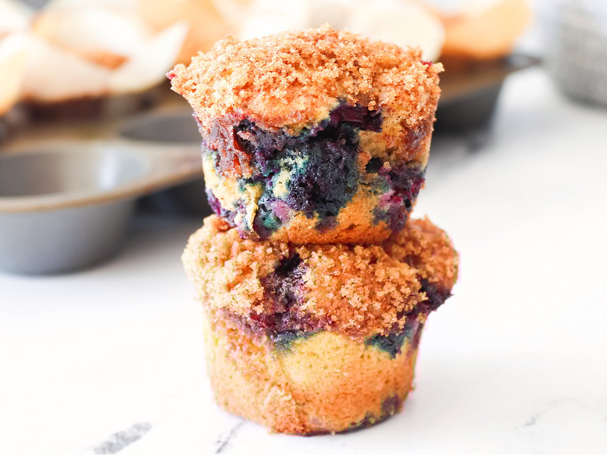 Two blueberry muffins stacked showing golden tops and juicy berries.