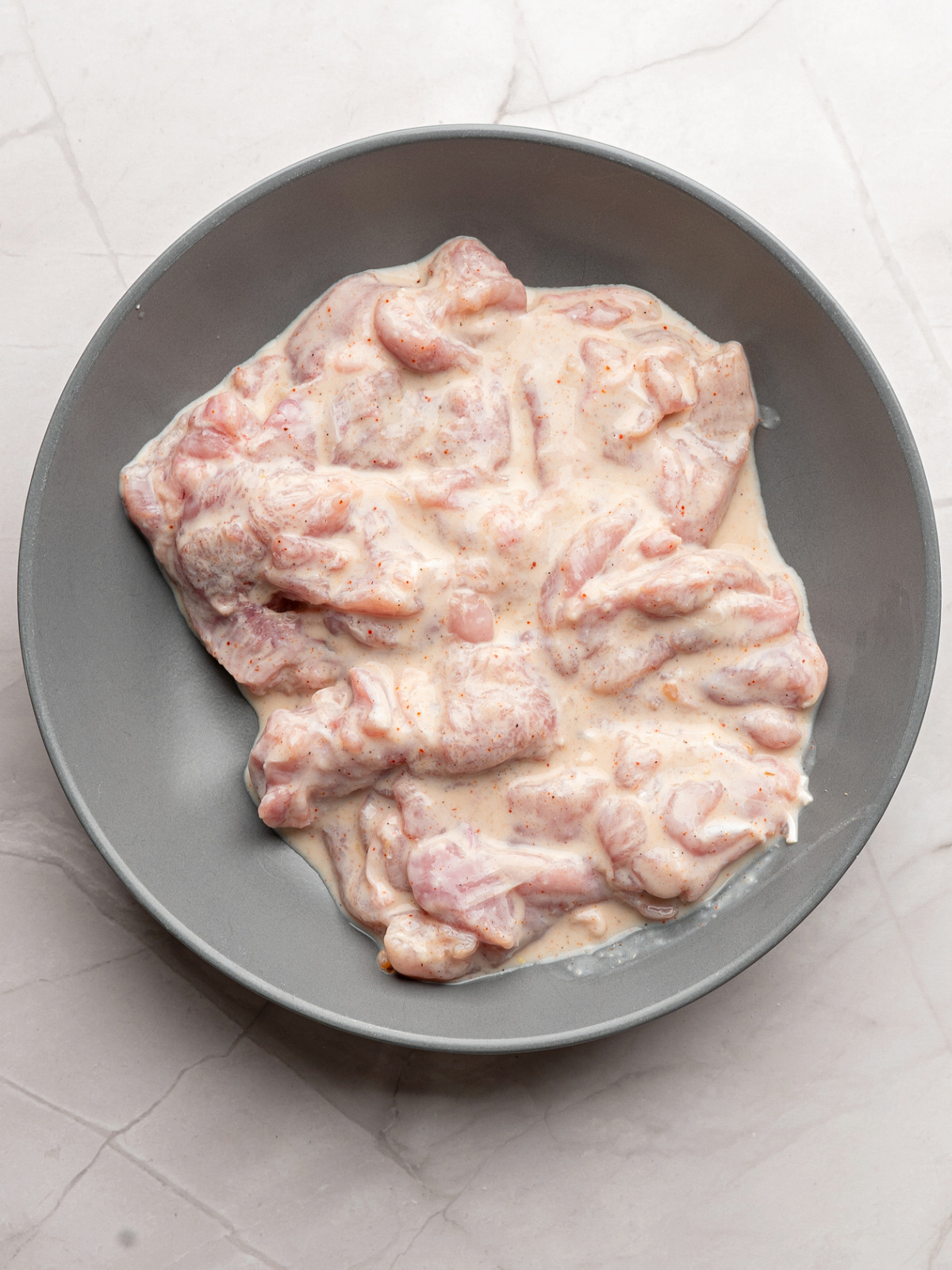 Chicken marinating in a buttermilk mixture.