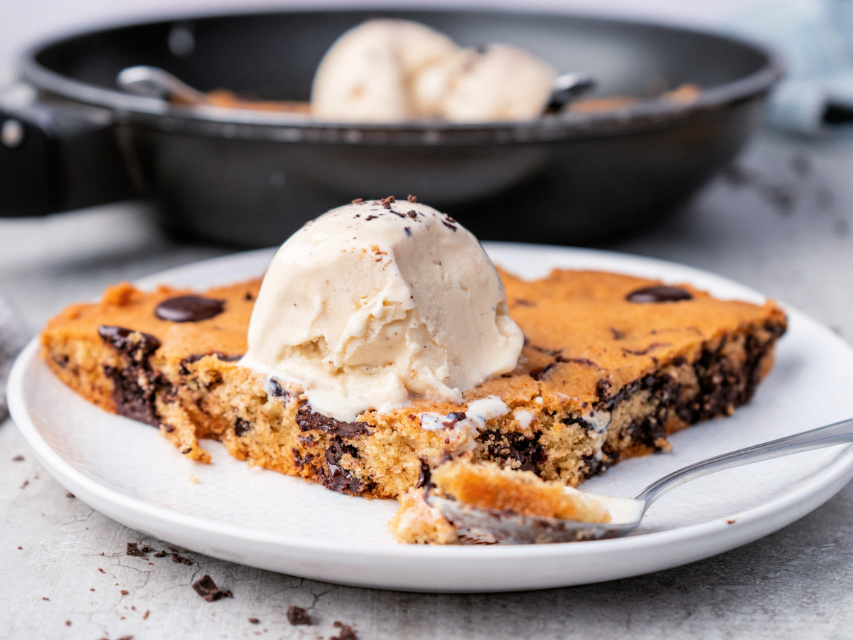 Slice of chocolate chip cookie topped with vanilla ice cream.
