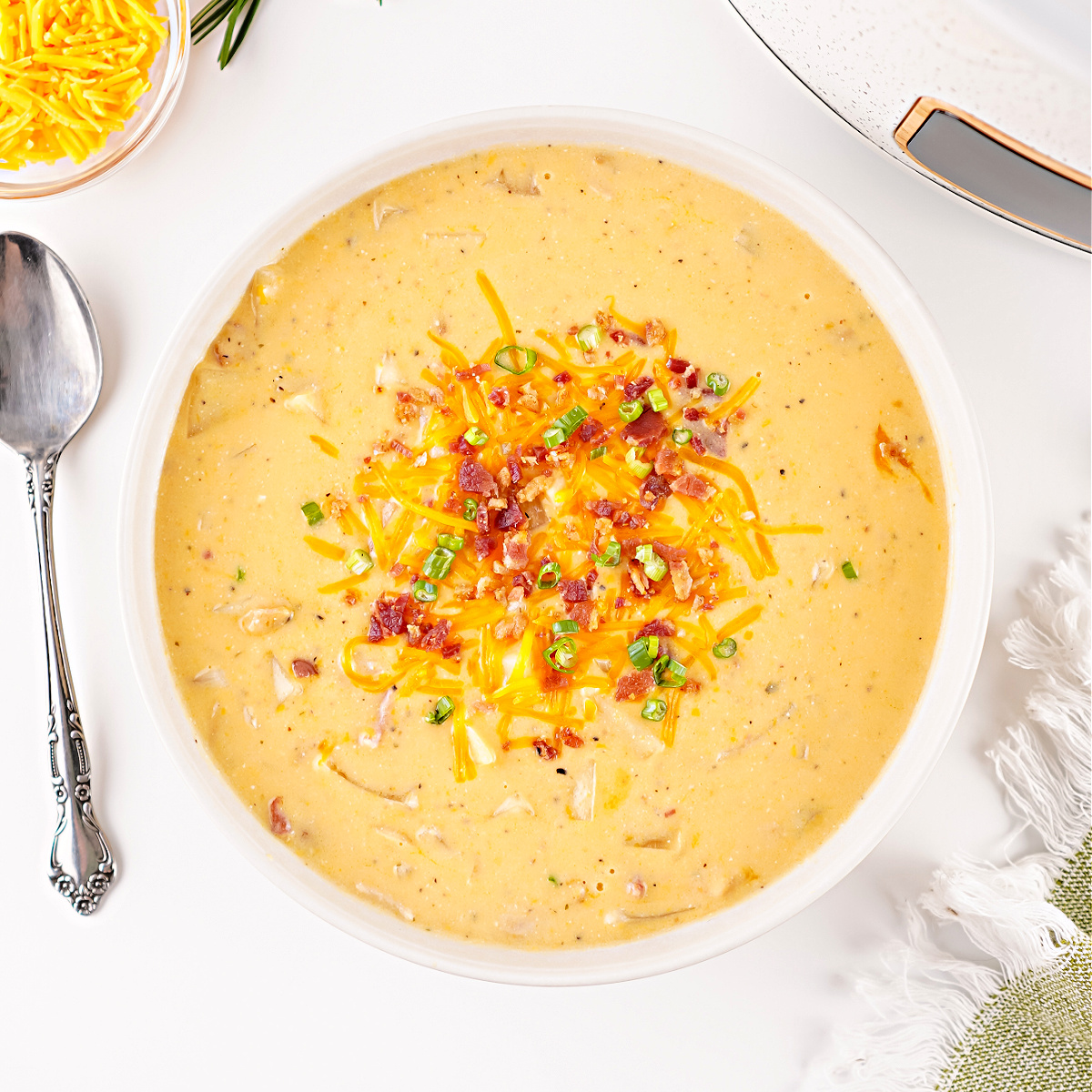A creamy bowl of irresistible Crockpot potato soup topped with melted cheese and bacon crumbles.