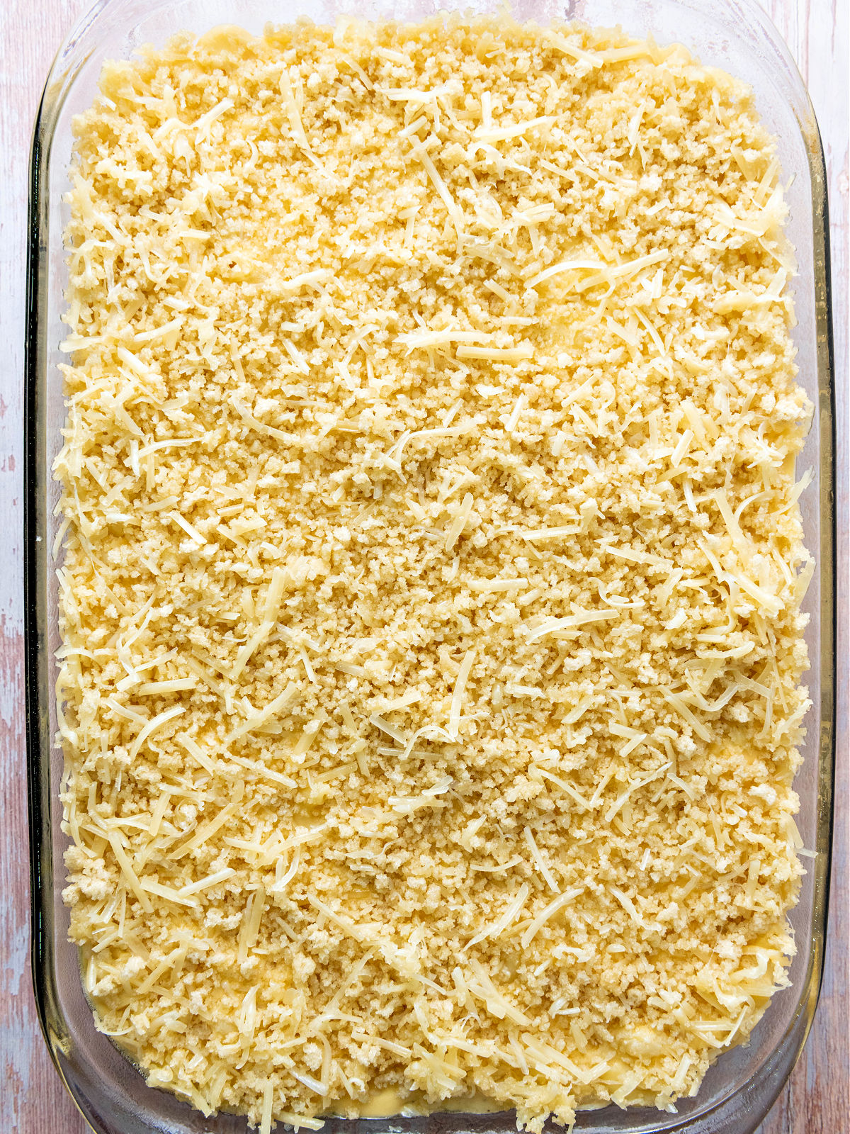 Cheese and bread crumbs on top of creamy macaroni in a baking dish prior to being baked.