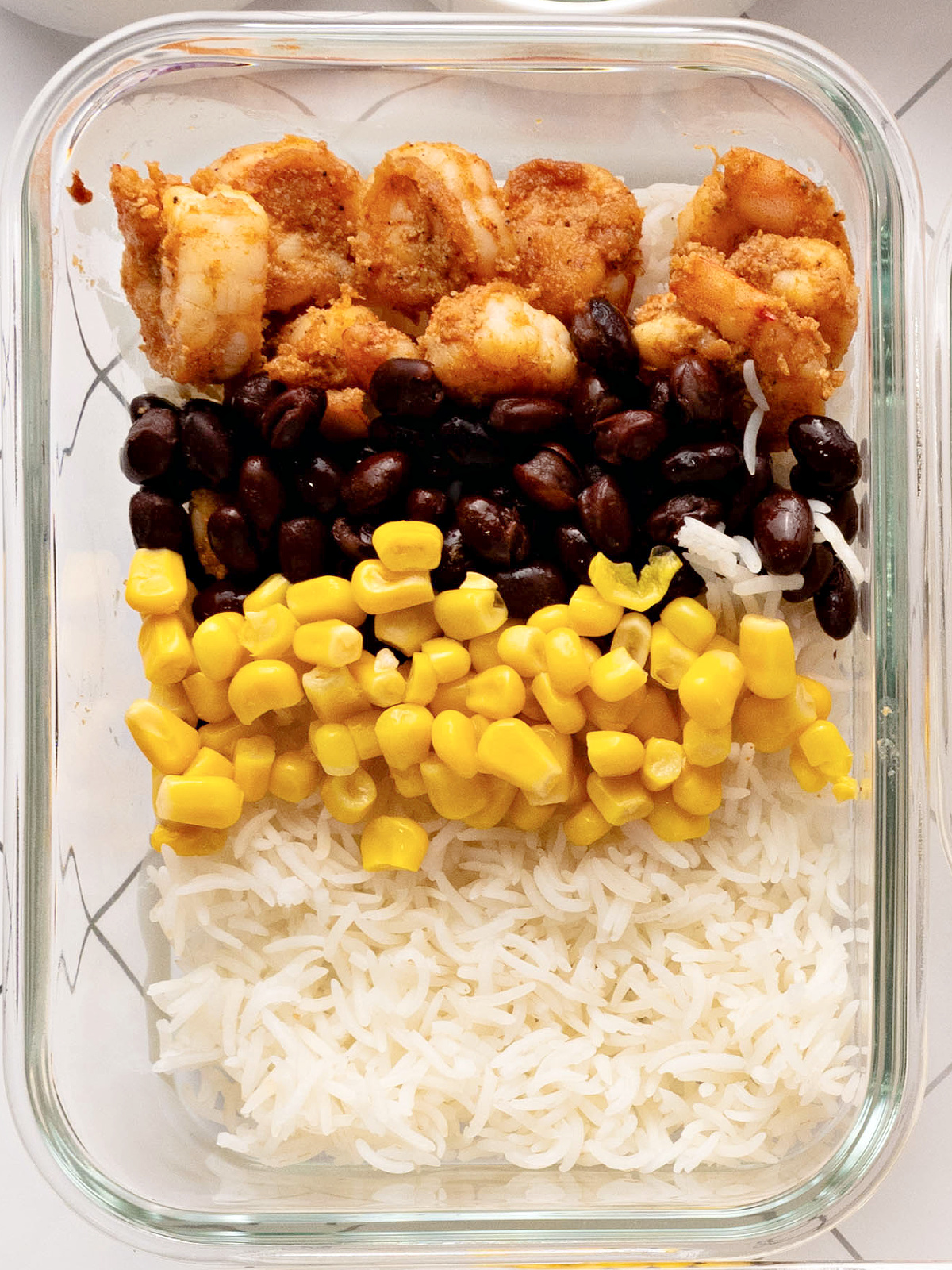Seasoned shrimp, black beans, and corn on a bed of white rice.
