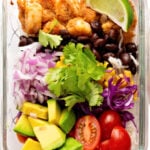 Shrimp, black beans, avocado, tomatoes, red onions, and lime in a glass dish.