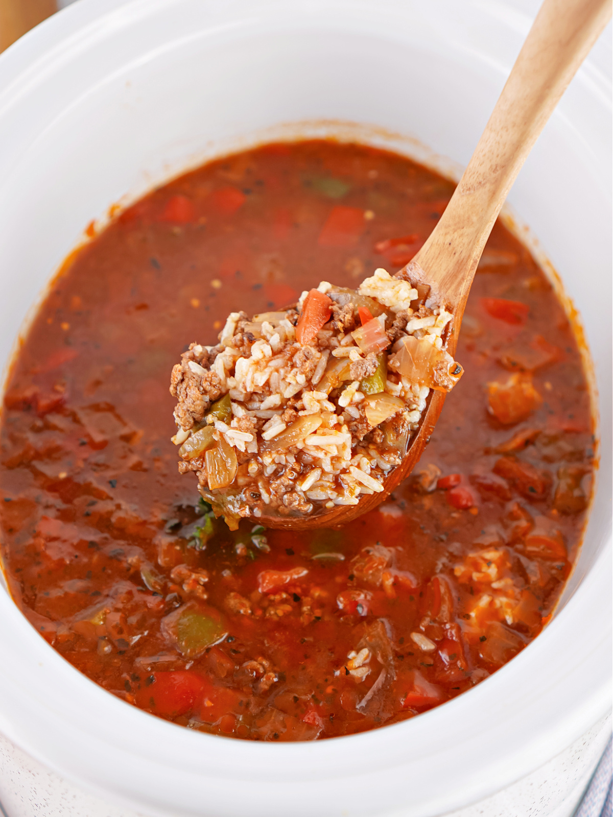 Ladle lifting a generous serving of Unstuffed Pepper Soup, showcasing the chunky mix of peppers, beef, and rice.