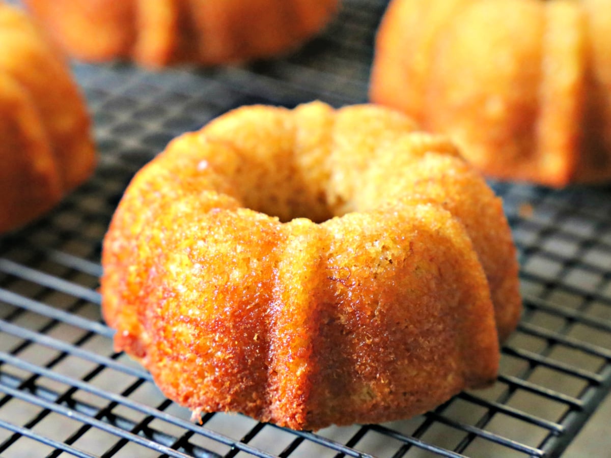Close-up of a single mini banana bundt cake resting on a wire rack, showing its detailed bundt design.